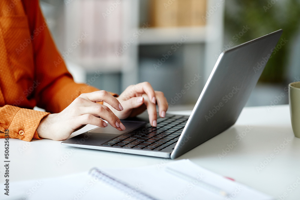 Medium close-up of unrecognizable young woman working in Internet texting on laptop in office Medium close-up of unrecognizable young woman working in Internet texting on laptop in office