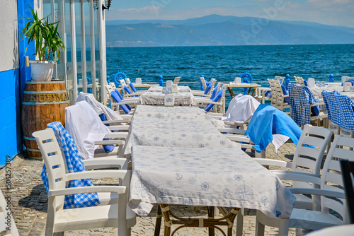 beautiful white tables on the beach, restaurant free and empty blue table and stairs taverne and sea background. mediterranean culture