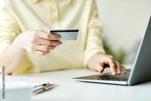 Unrecognizable woman buying something in online shop on laptop paying for items with credit card