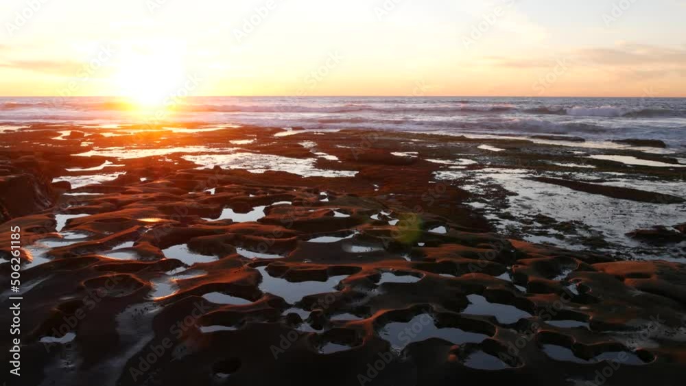 Eroded rock formation, tide pool in La Jolla, California coast, USA. Littoral intertidal zone erosion, unusual relief shape of tidepool. Water in cavity, hollows and holes on stone surface, sunset sky Eroded rock formation, tide pool in La Jolla, California coast, USA. Littoral intertidal zone erosion, unusual relief shape of tidepool. Water in cavity, hollows and holes on stone surface, sunset sky
