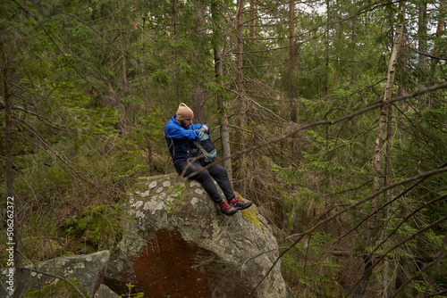 Young male adventurer sitting on the rock