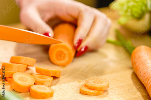Woman cutting carrot on kitchen board