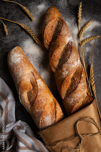 Canvastavla French baguette, long loaf with
wheat ears on black background with flour on the
