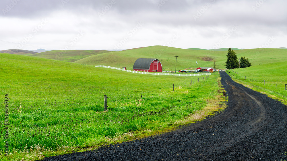 Long graven driveway leads to a farm with a red barn
