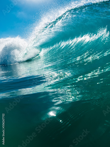 Barrel wave in ocean. Breaking blue wave with sunlight