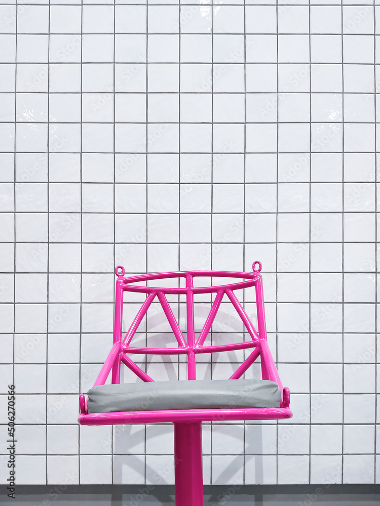 Background of modern pink metal bar chair on white tile wall in minimal style and vertical frame Background of modern pink metal bar chair on white tile wall in minimal style and vertical frame