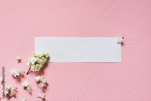 lilac flowers with white card. Creative congratulations layout from lilac on white papper. Spring flower concept. Flat lay, top view, copy space