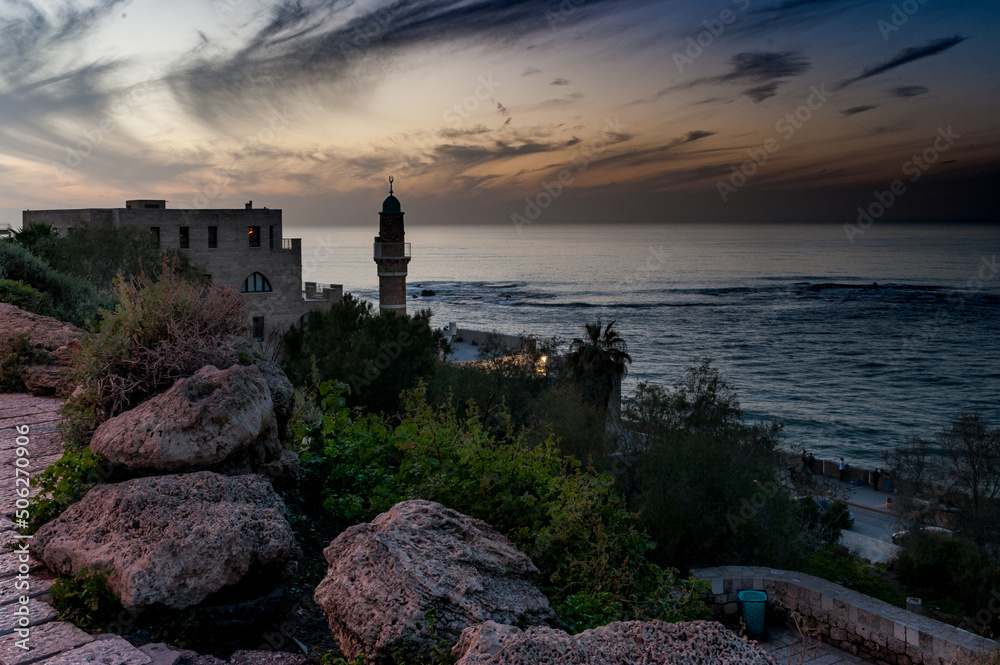 Twilight colors the sky off the coast of Jaffa, Israel with a view of a mosque minaret and the Mediterranean sea.
