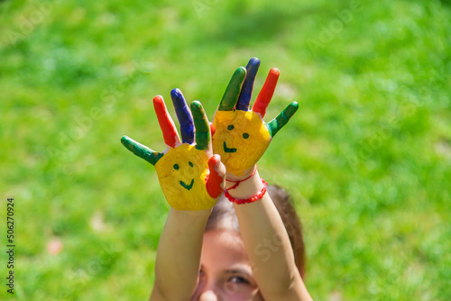 Hands of a child with a painted smile. Selective focus.