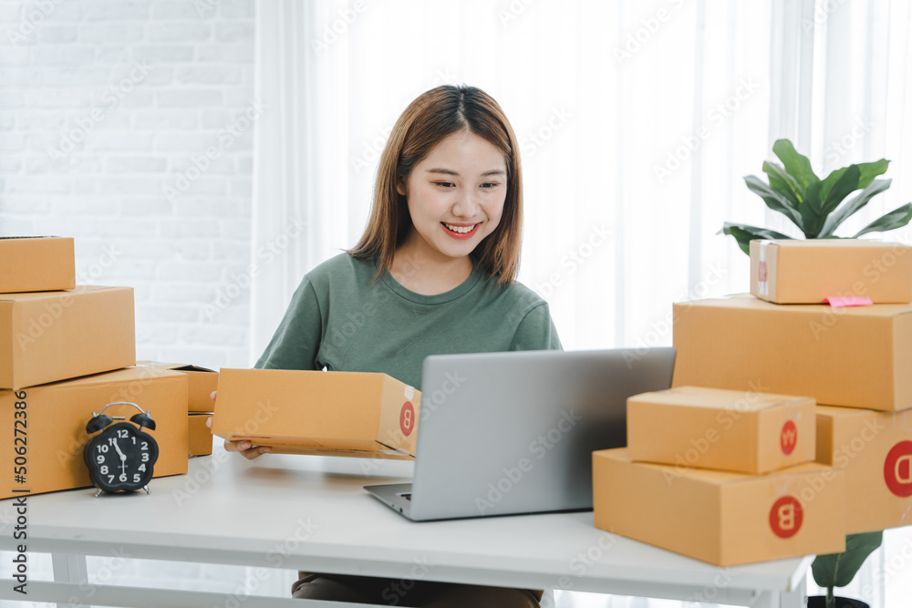 Portrait of a Small Business Startup, SME Owner, Female Entrepreneur work on parcel boxes Receipts and check orders online to prepare boxes. Selling to customers. Online SME business idea. Portrait of a Small Business Startup, SME Owner, Female Entrepreneur work on parcel boxes Receipts and check orders online to prepare boxes. Selling to customers. Online SME business idea.