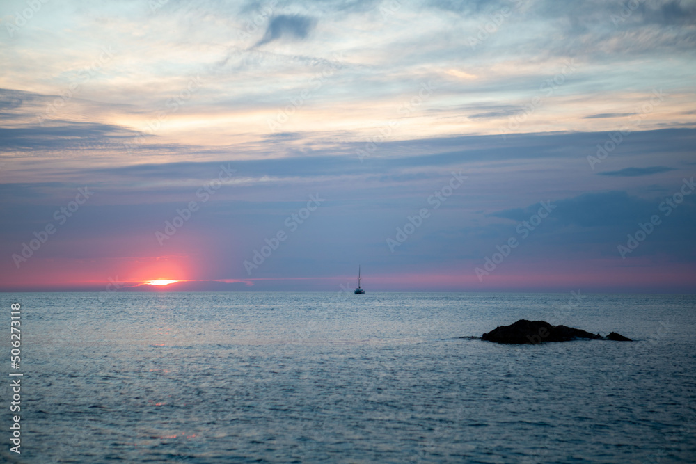 Naklejka premium view of the sunset above the sea yacht on the background