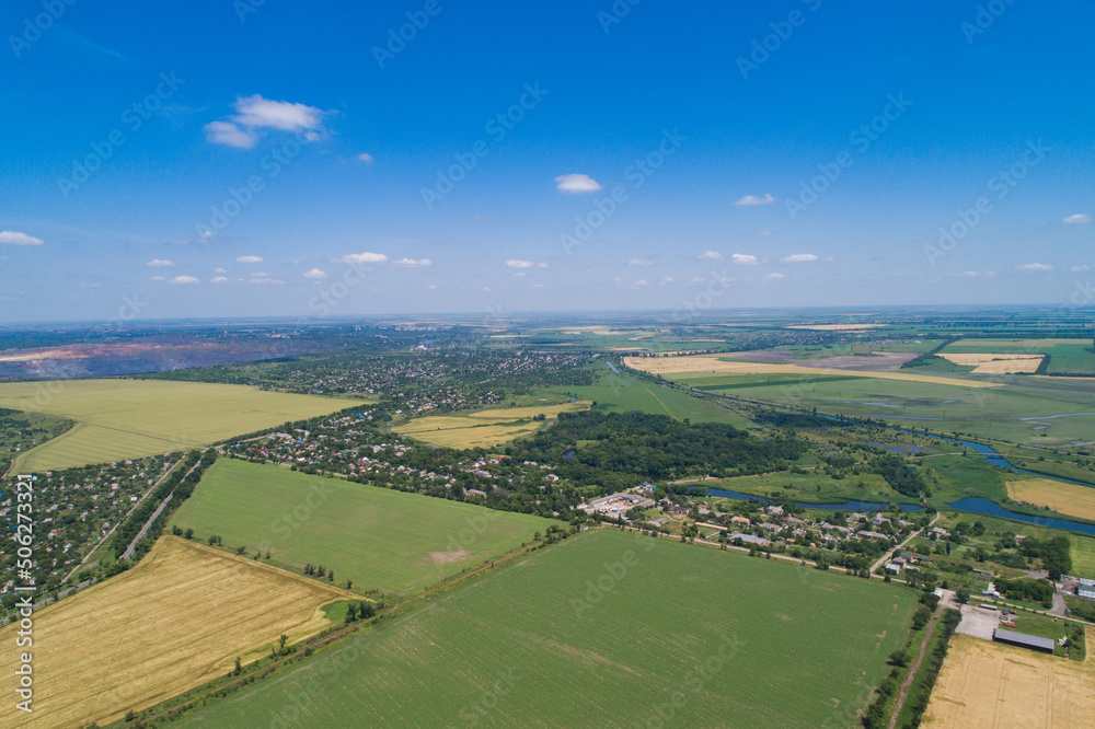 The countryside on a bright sunny day, fields and villages. Steppe plain area with a river. Bird's eye view. View from a drone.