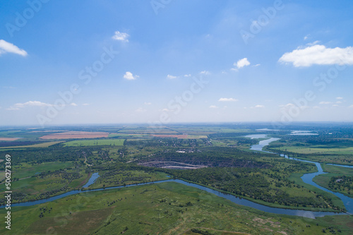The countryside on a bright sunny day, fields and villages. Steppe plain area with a river. Bird's eye view. View from a drone.