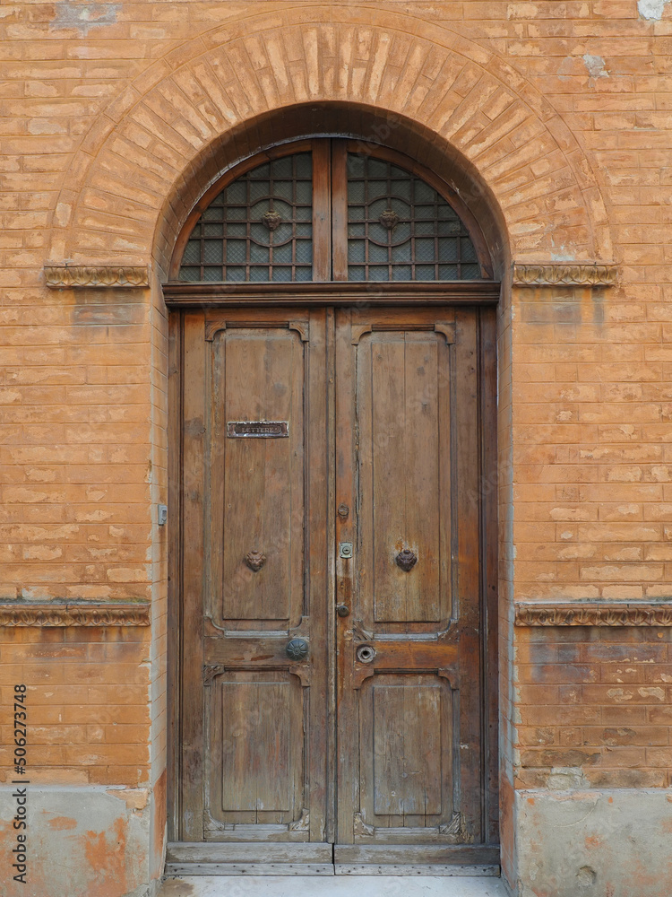 Cracked and damaged wooden door with post hole. Lettere means letters.