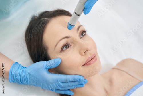 Woman receiving facial treatment in cosmetology clinic