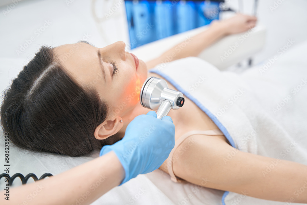 Adult woman getting face lifting treatment in beauty salon