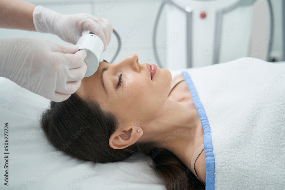 Resting woman in beauty parlor undergoing forehead therapy Resting woman in beauty parlor undergoing forehead therapy