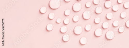 Drops of water or cosmetic liquid on pink background.