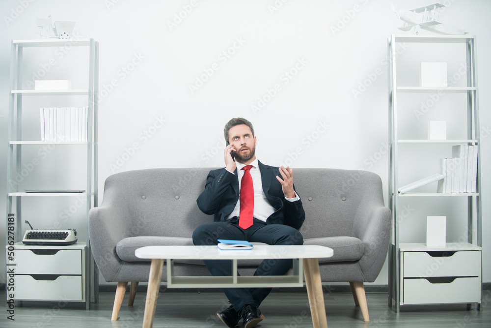 businessman sitting in office and talking on phone businessman sitting in office and talking on phone