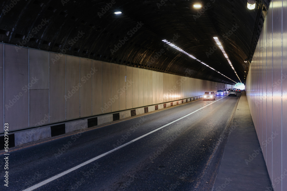 Road tunnel in mountain illuminated by lamps