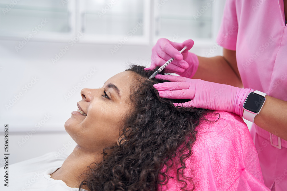 Naklejka premium Cosmetologist performs mesotherapy procedure on the scalp of a patient
