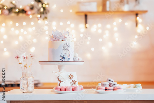Cake on bokeh background. Festive meal. Cake with flowers and a picture, pasta and lollipops