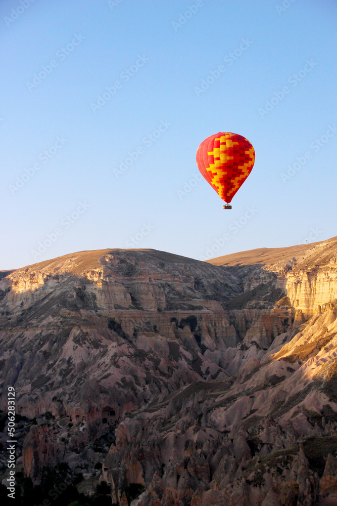 Colorful hot air balloon floating over a brown mountain range