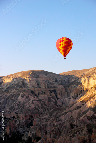 Colorful hot air balloon floating over a brown mountain range