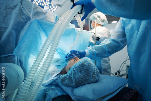 Surgeon pressing mask of oxygen-breathing apparatus to patient face