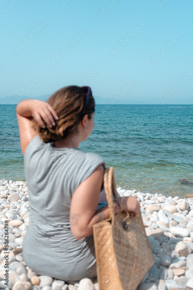 Day on a natural beach. Young girl alone on the beach with her beach bag. Relaxation