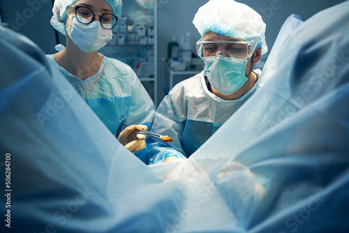 Nurse taking out bloody gauze with forceps during operation