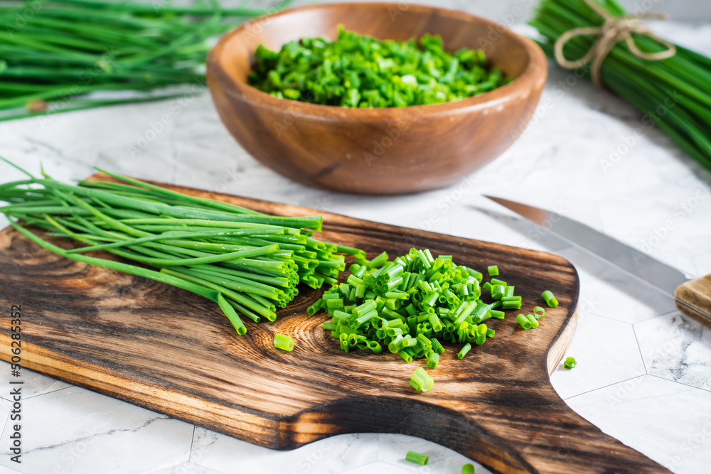 Sliced fresh green onions on a cutting board on the table. Spring vitamin harvest. Close-up Sliced fresh green onions on a cutting board on the table. Spring vitamin harvest. Close-up