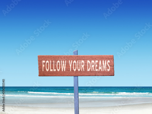 Follow Your Dreams motivational quote on sign in nature.