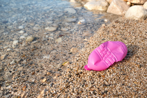 Plastic bottle pink on the seashore. Beach pollution.
