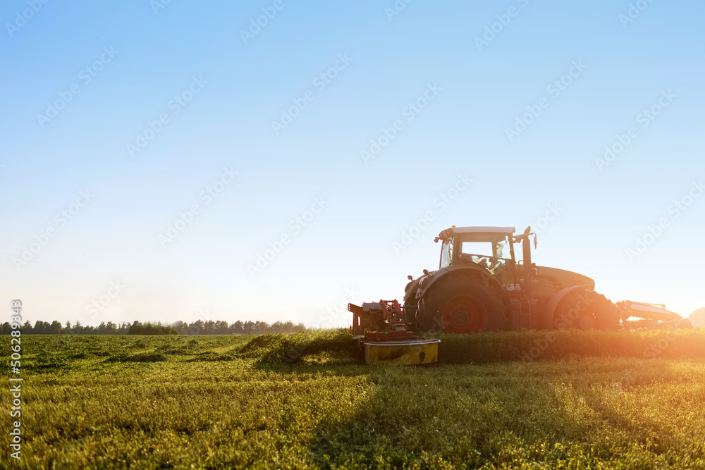 Obraz premium tractor makes harvesting hay for animals on a farm