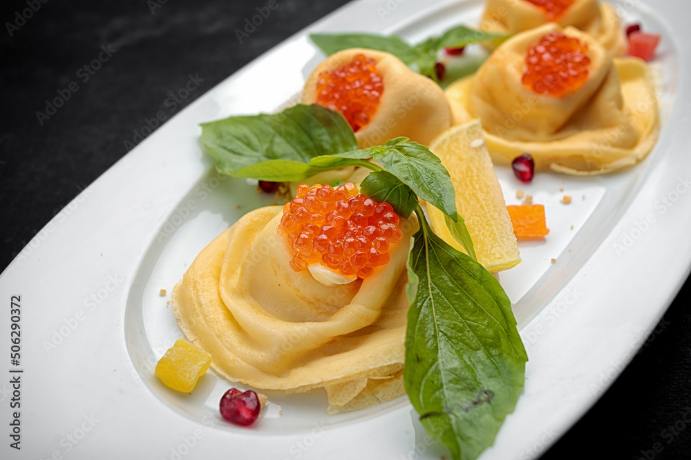 Pancakes with red caviar, basil, dark background Pancakes with red caviar, basil, dark background