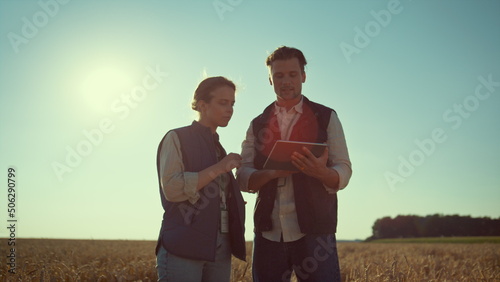 Agronomists team holding tablet computer in sunlight. Agritech industry workers photo