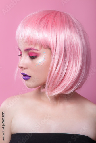 attractive young woman with pink bob cut and purple lips looking at camera isolated on pink background
