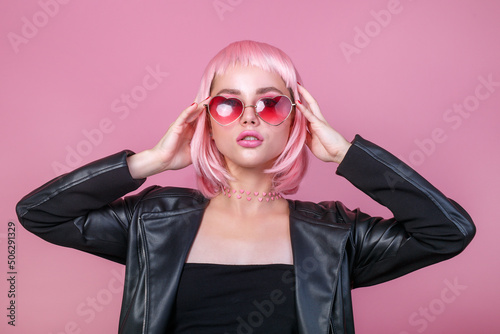 Stylish portrait of woman in sunglasses with bright colored pink hair and pink make-up in sunglasses