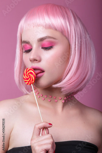 Beauty glamour woman with pink hair and beautiful makeup holding pink sweet colorful lollipop candy