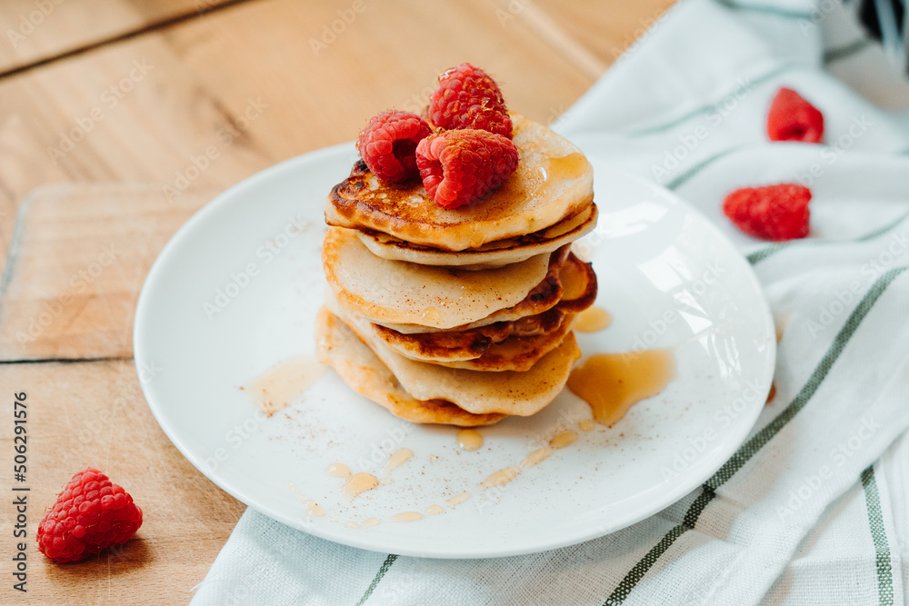 Pancakes with raspberries lying on the table, stacking