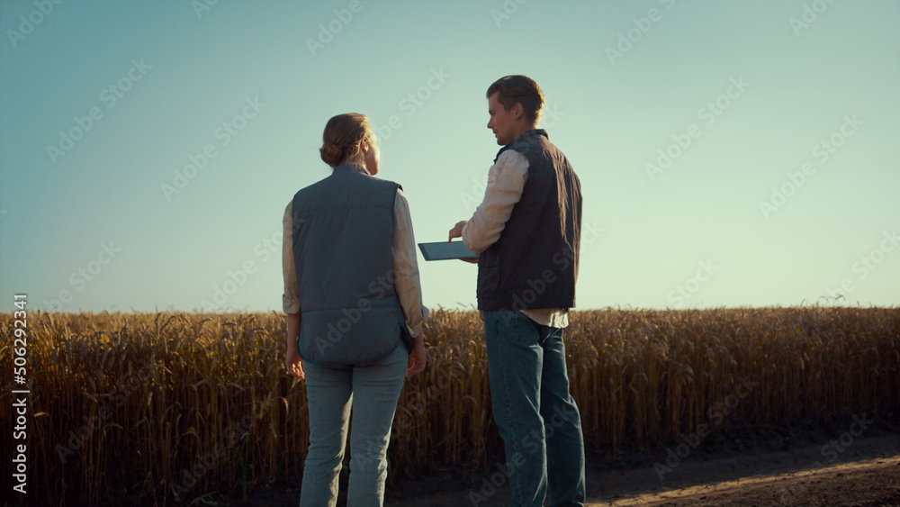 Agronomist team discussing field works rear view. Agritech managers using tablet Agronomist team discussing field works rear view. Agritech managers using tablet