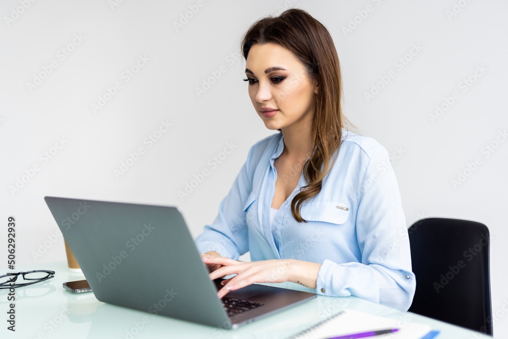 Business woman using laptop computer and sitting by the table in office Business woman using laptop computer and sitting by the table in office