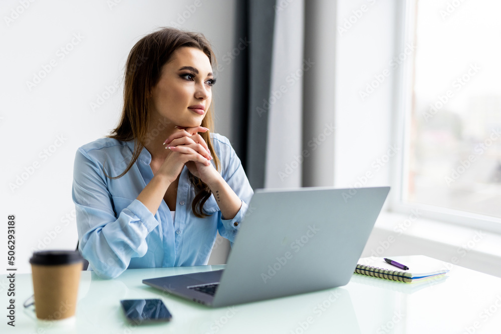 Business woman using laptop computer and sitting by the table in office Business woman using laptop computer and sitting by the table in office