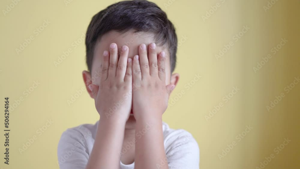 Cute boy smiling and covering his face on colour background. Cute boy smiling and covering his face on colour background.