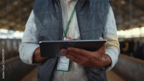Hands tapping tablet screen closeup. Focused livestock manager work in cowshed.