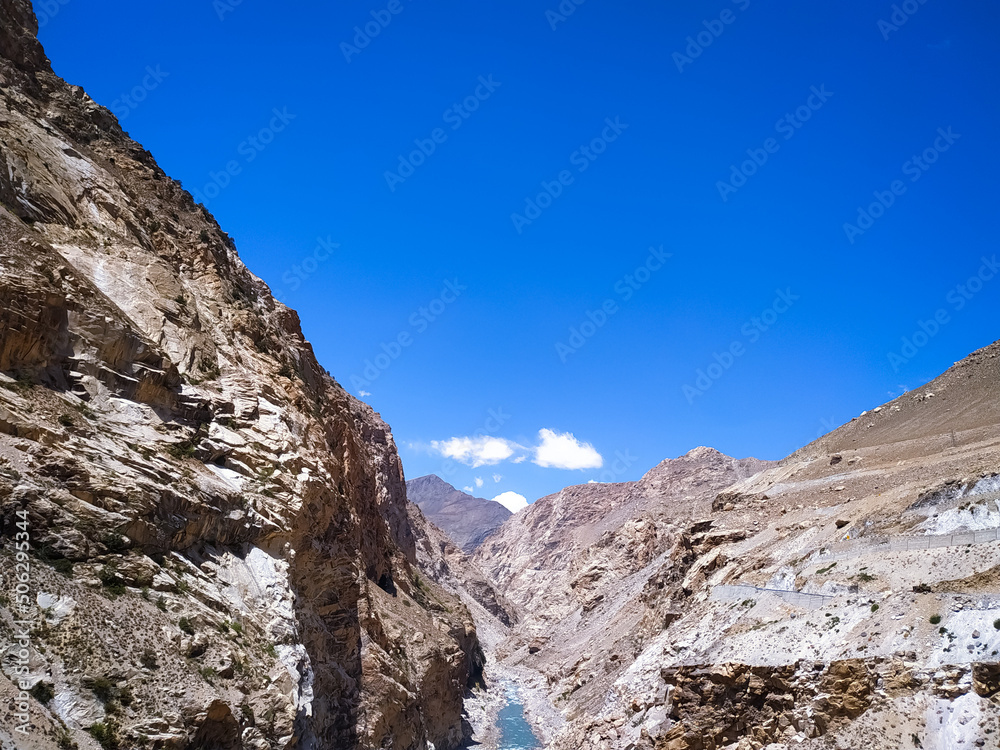 A river between valleys on blue sky background with clouds