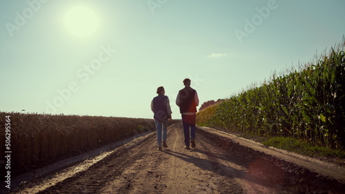 Agronomists walking ground road together. Farmers silhouettes inspecting harvest