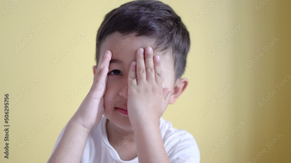Cute boy smiling and covering his face on colour background. Cute boy smiling and covering his face on colour background.