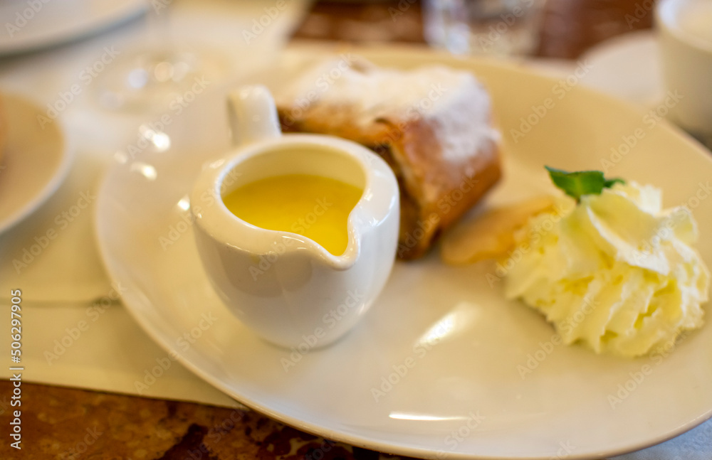 Austrian sweet dessert, portion of apple strudel with whippen cream and hot vanilla sauce served in old bakery cafe in Vienna, Austria Austrian sweet dessert, portion of apple strudel with whippen cream and hot vanilla sauce served in old bakery cafe in Vienna, Austria